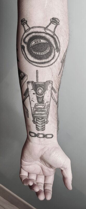 Un tatouage handpoke d'une manchette de bras geek, motifs jeux video, full metal Alchemist, Bioshock et Borderland