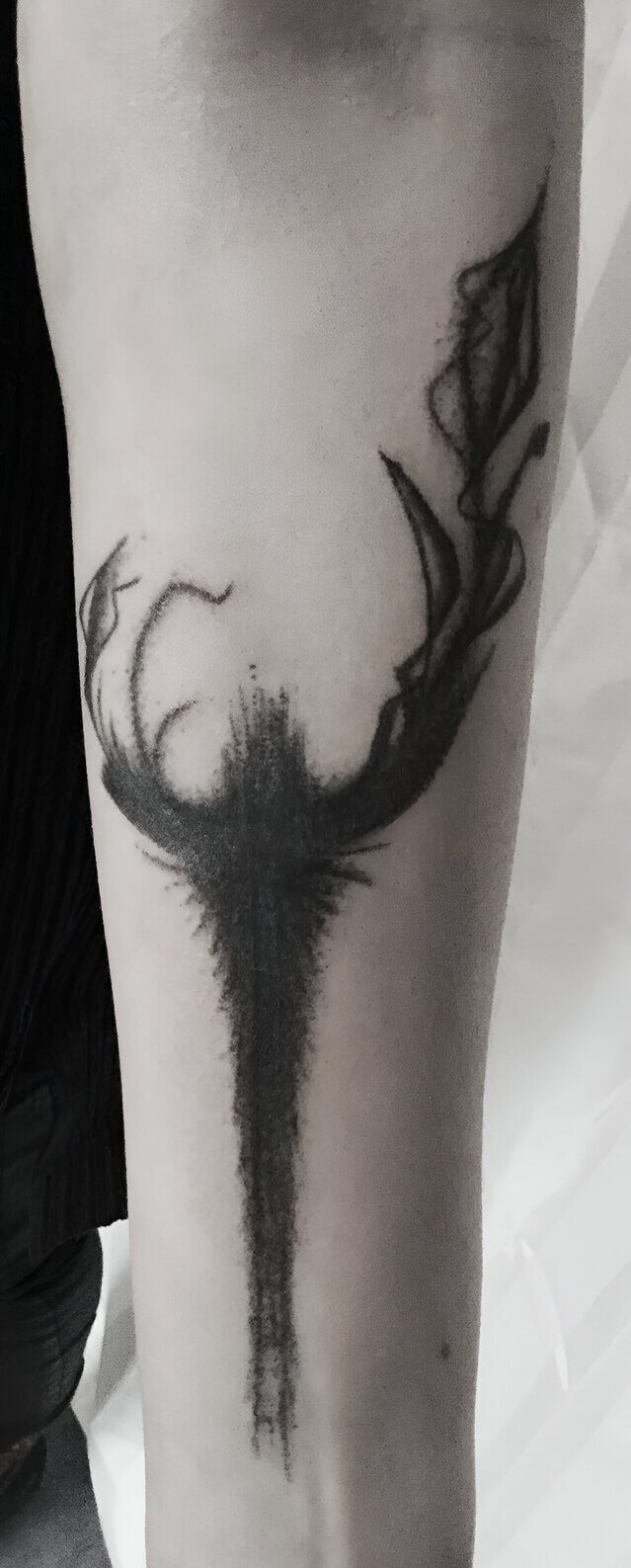 Un motif noir abstrait dark tatoué sur l'avant bras au handpoke