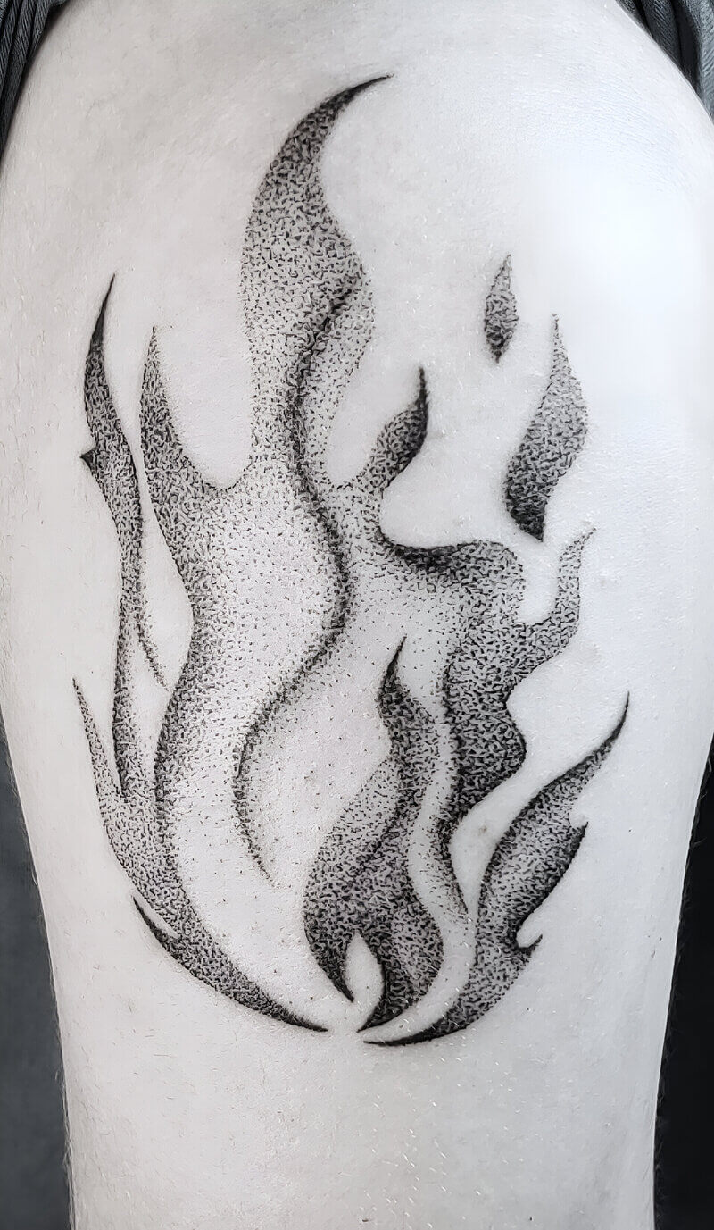 Un tatouage handpoke dotwork d'une flamme sur le haut du bras