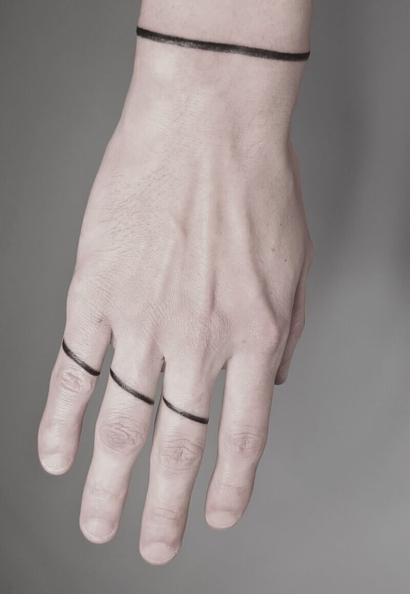 Un tatouage handpoke de lignes minimalismes noires sur les doigts d'une main