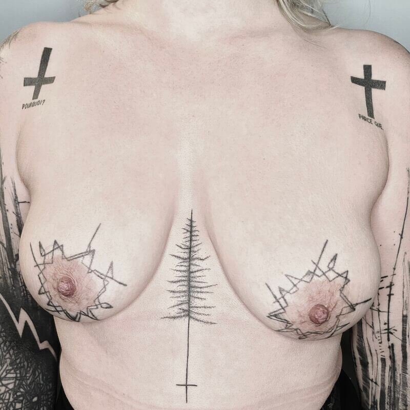 Un tatouage handpoke d'un buste et epaules, motifs croix, sapin et lignes