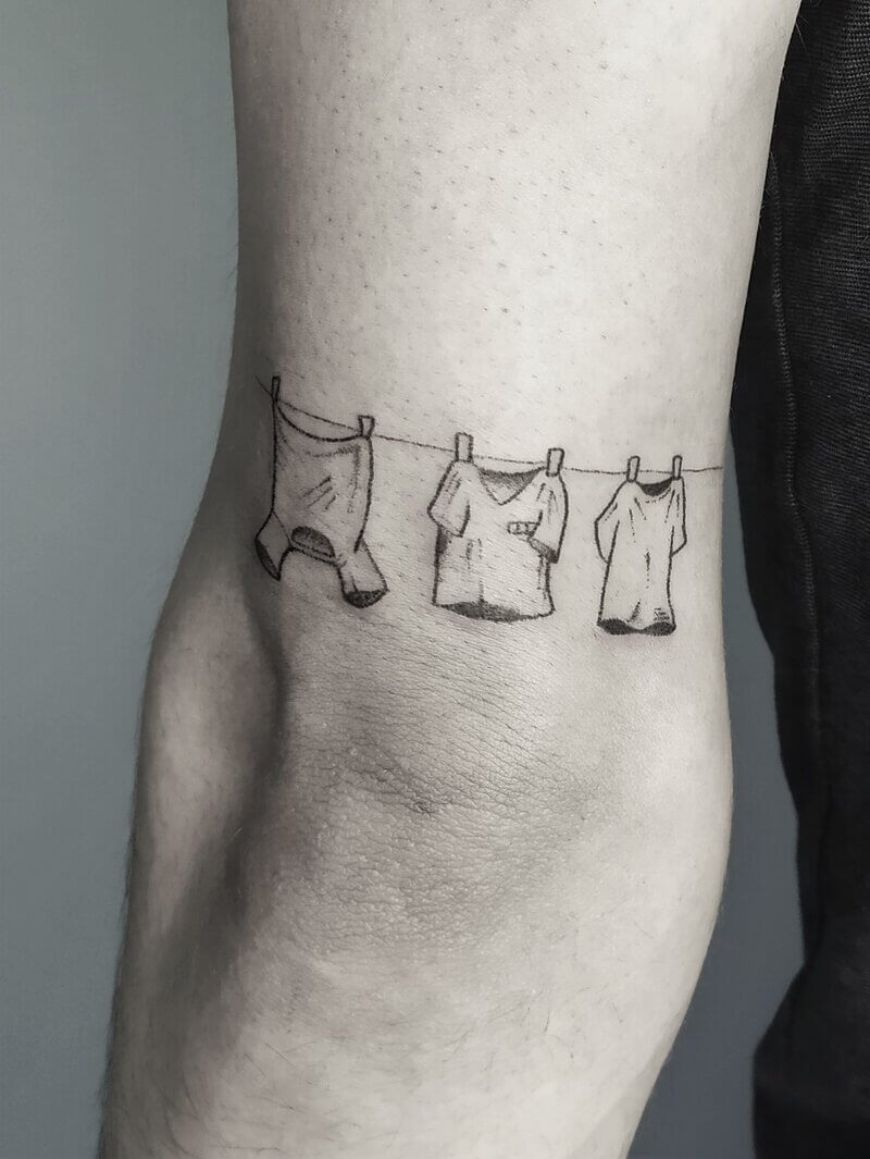 Un tatouage handpoke de trois t-shirt en linge suspendu sur le bras