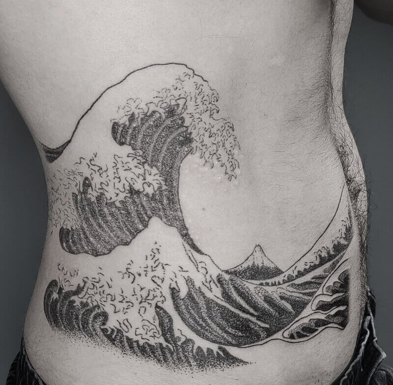 Un tatouage handpoke de la vague d'Hokusai sur le ventre, grande pièce