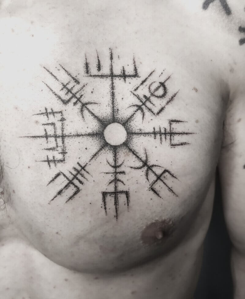 Un tatouage handpoke d'un Vegvisir, une boussole runique viking ou nordique sur le pectoral